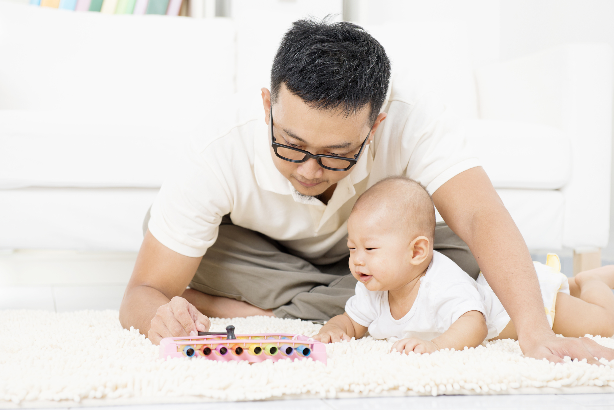 Father and baby playing music instrument. Sound development concept. Asian family lifestyle at home.