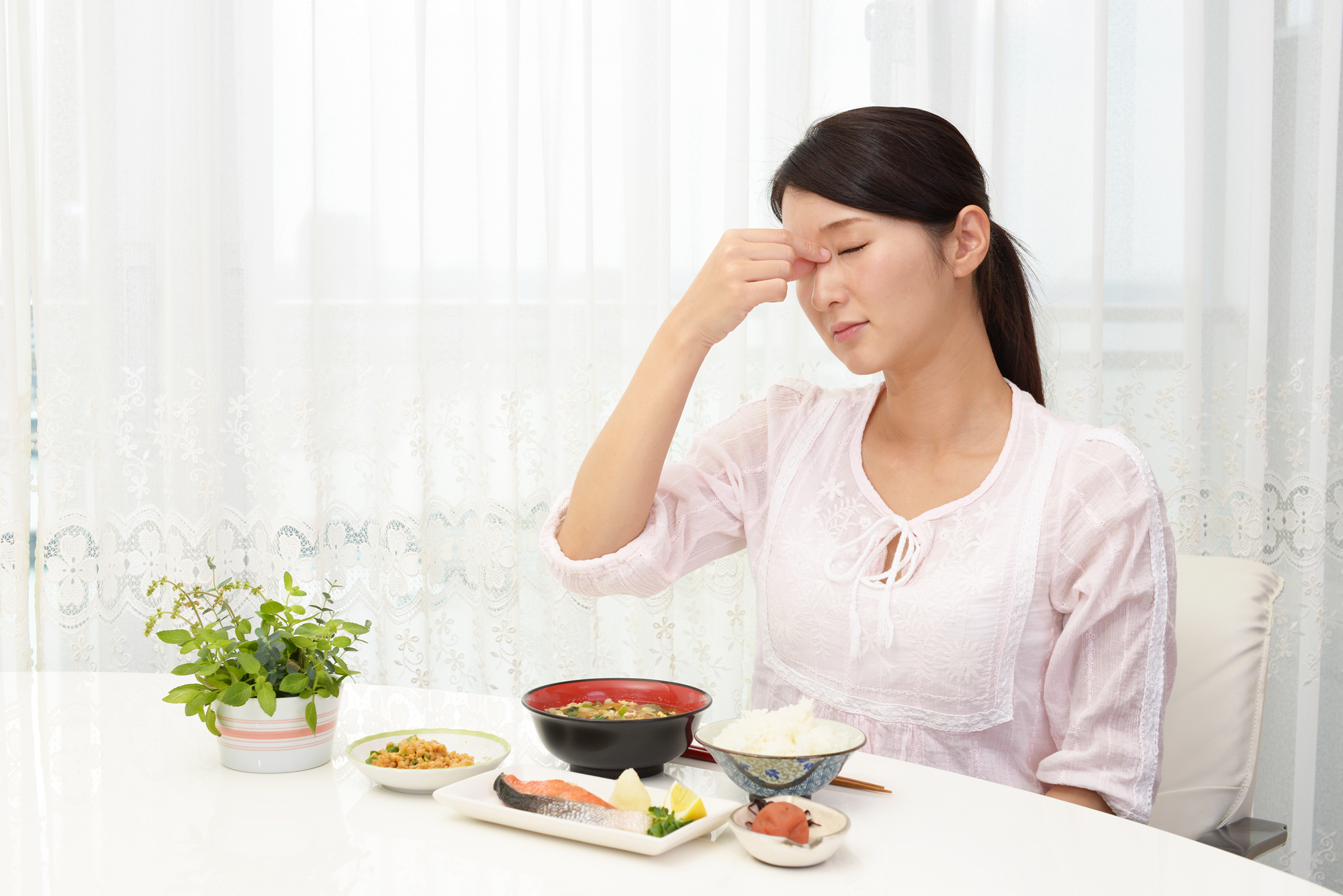 体調が悪い食事中の女性