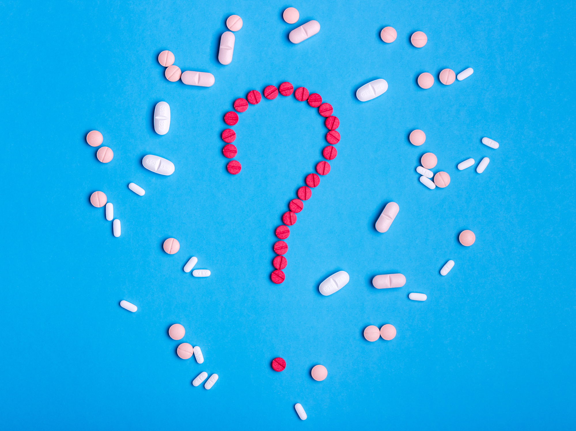 Question mark made from red medicine pills on a blue background